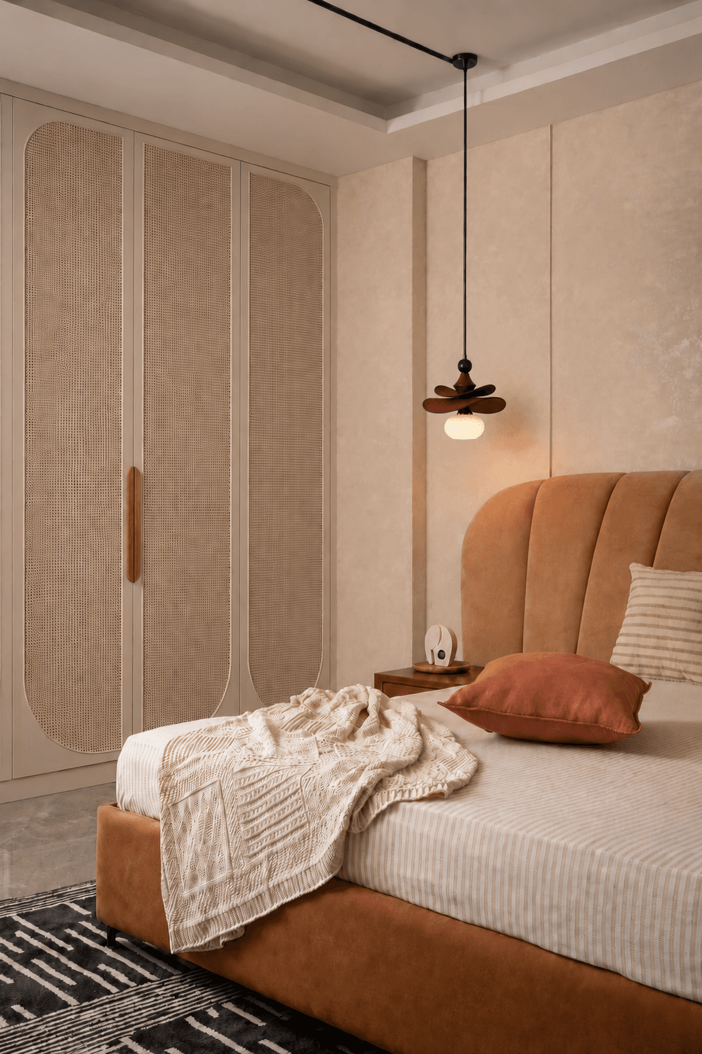 Warm contemporary bedroom with a rust upholstered bed, arched cane wardrobe panels, and a petal pendant light